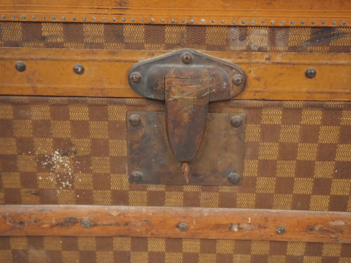 MOYNAT.  Malle de voyage en toile enduite, à décor de damier.  Poignée