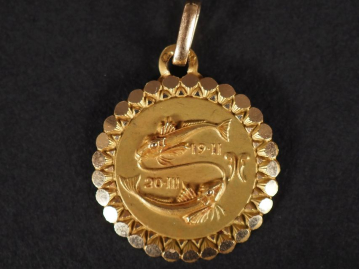 Médaillon en or jaune 750, à décor de poissons et agrémenté de dates. 
