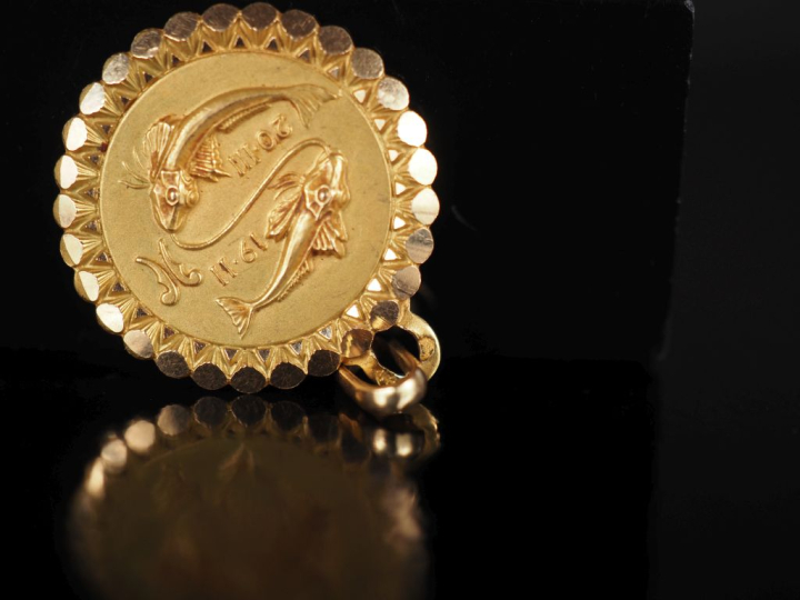 Médaillon en or jaune 750, à décor de poissons et agrémenté de dates. 