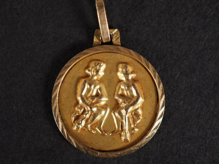 Petit médaillon en or jaune 750, figurant deux jeunes femmes assises. 