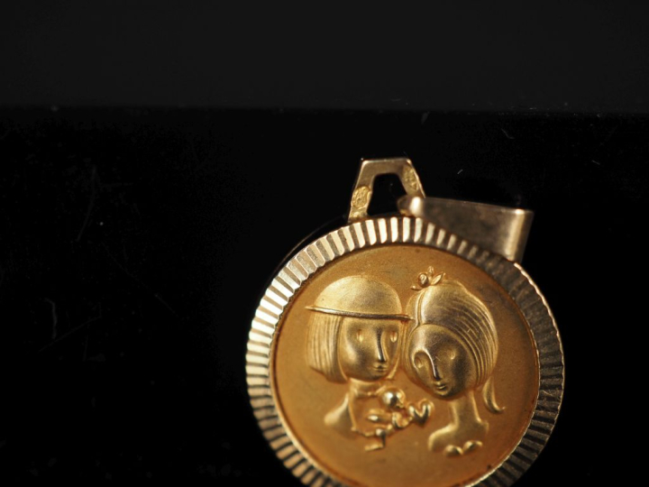Médaille en or jaune 750, figurant un couple.  Diam. 1,5 cm Poids. 1,1