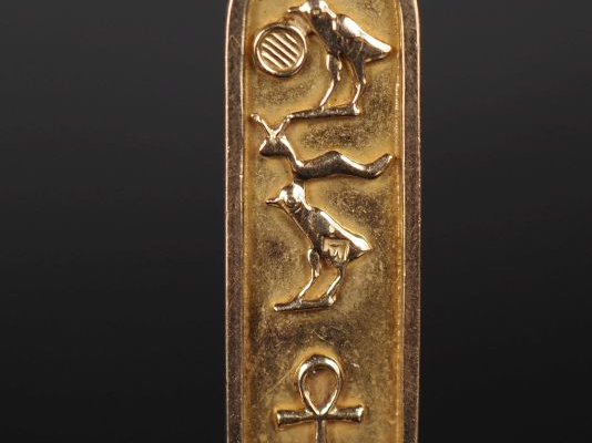 Pendentif en or jaune 750, à décor de hiéroglyphes.  H. 3,7 cm Poids. 