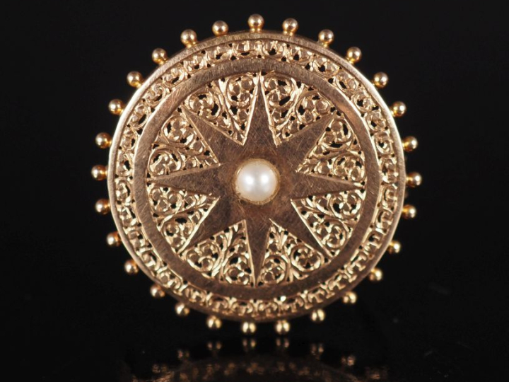 Broche ronde en or jaune 750, à décor ajouré d'une étoile sertie en so