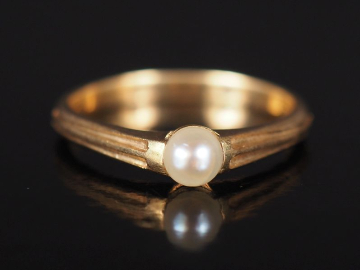 Bague jonc en or jaune 585, sertie en son centre d'une perle blanche. 