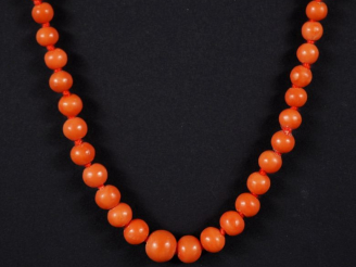 Vente aux enchères Collier de perles de corail disposées en chute. Fermoir et chainette d