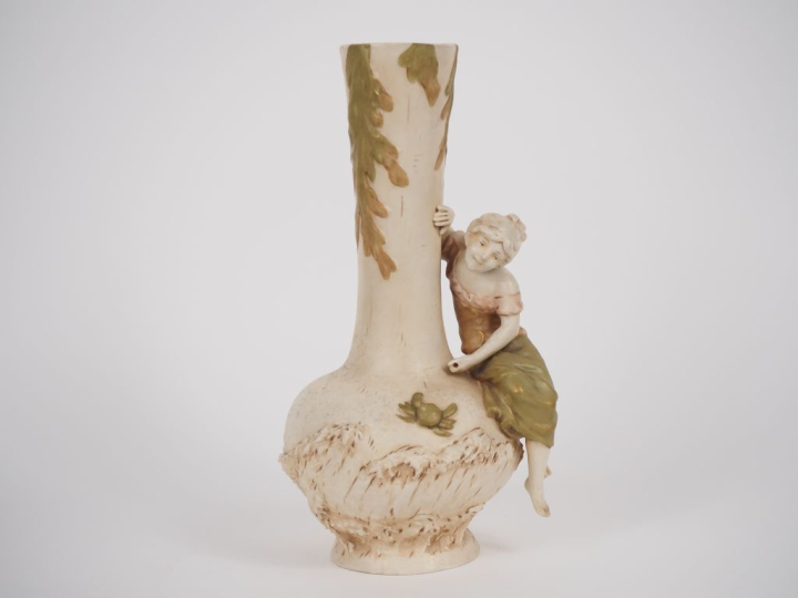 ROYAL DUX. Vase en biscuit polychrome à décor de jeune fille au crabe.