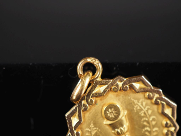 Médaille religieuse en or jaune 750, à décor de calice.  Joli pourtour