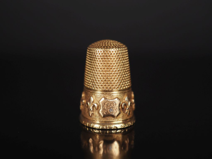 Dé à coudre en or jaune 750, à décor d'une frise de fleurs de lys. H. 