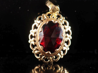 Vente aux enchères Pendentif en or jaune 750, serti en son centre d'un grenat.  Joli pour