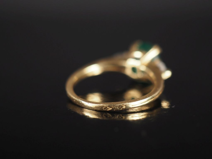 Bague en or jaune 750, serte en son centre d'une émeraude épaulée de d
