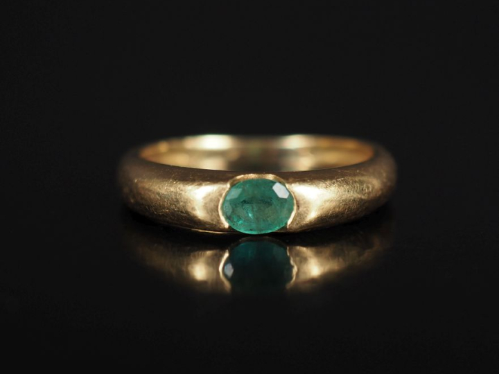 Bague jonc en or jaune 750, sertie en son centre d'une émeraude.  TDD.