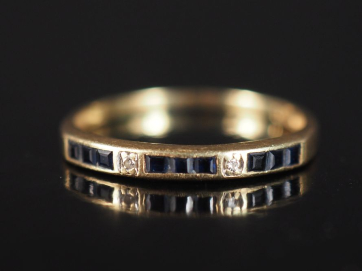 Demi alliance en or jaune 750, sertie de saphirs calibrées et deux pet