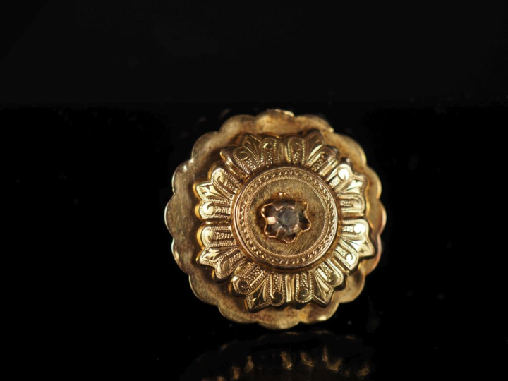 Broche ronde à bord festonné en or jaune 750, sertie en son centre d'u