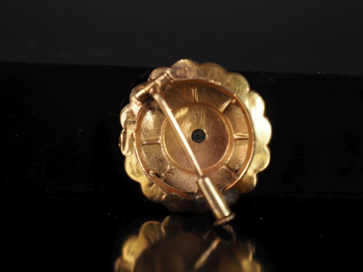 Broche ronde à bord festonné en or jaune 750, sertie en son centre d'u