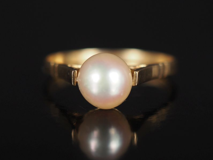 Bague en or jaune 750, sertie en son centre d'une perle blanche.  TDD.
