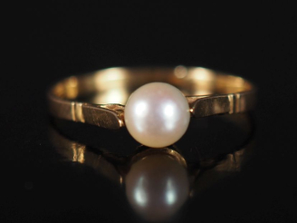 Vente aux enchères Bague en or jaune 750, sertie en son centre d'une perle blanche.  TDD.