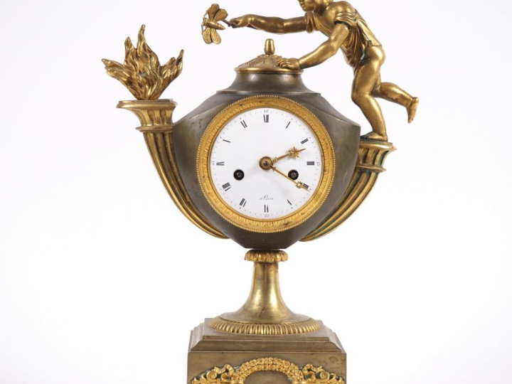 Pendule de style Empire en bronze, à double patine, figurant un amour 