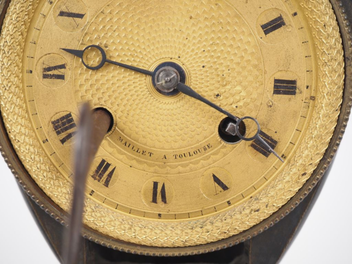 Pendule de style Empire en bronze patiné et doré,  en forme d'écus, à 