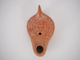Vente aux enchères Lampe en terre cuite orné d’un visage de face sur le médaillon. Traces