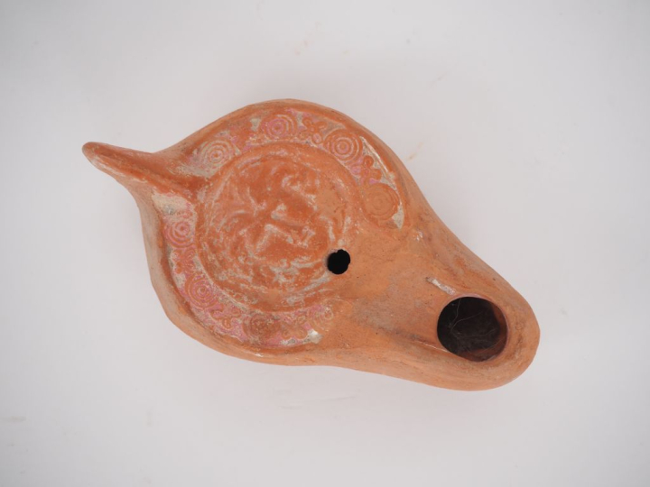 Lampe en terre cuite orné d’un visage de face sur le médaillon. Traces