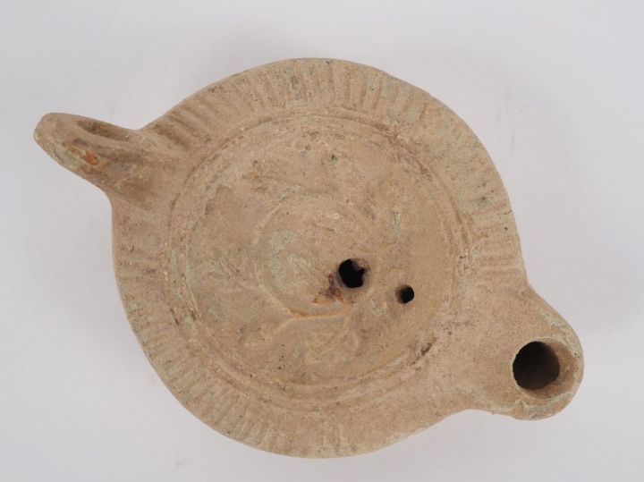 Lampe romaine en terre cuite au médaillon orné d’un couronne végétale.