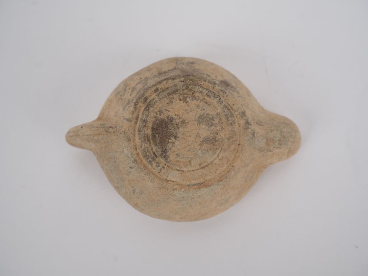 Lampe romaine en terre cuite au médaillon orné d’un couronne végétale.