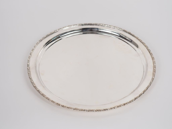 Grand plat rond en métal argenté, à décor d'une frise de feuillage et 