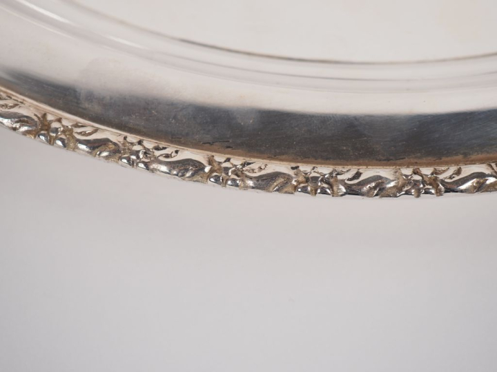 Grand plat rond en métal argenté, à décor d'une frise de feuillage et 