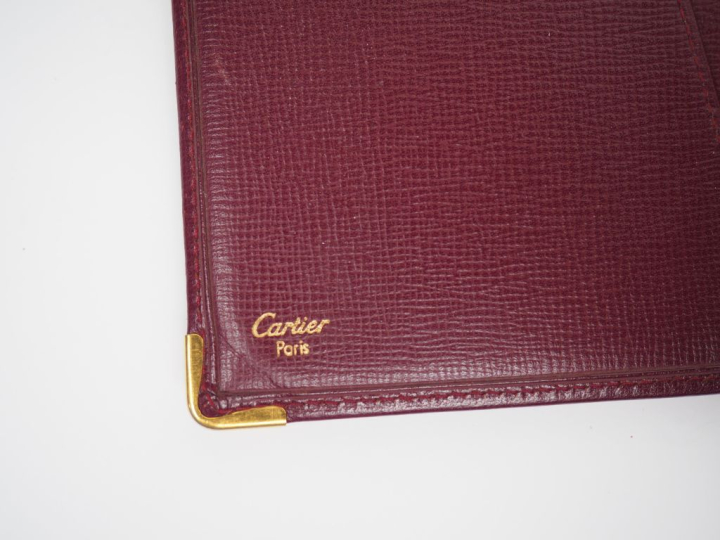 CARTIER, Paris Protège agenda et porte-cartes en cuir bordeaux.  Ferme