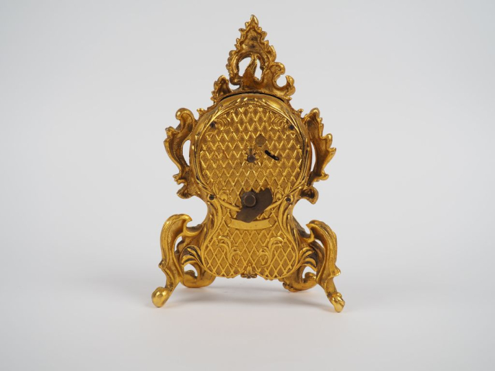 LANCEL, Paris Pendulette de style Louis XV en métal doré. Cadran rond 