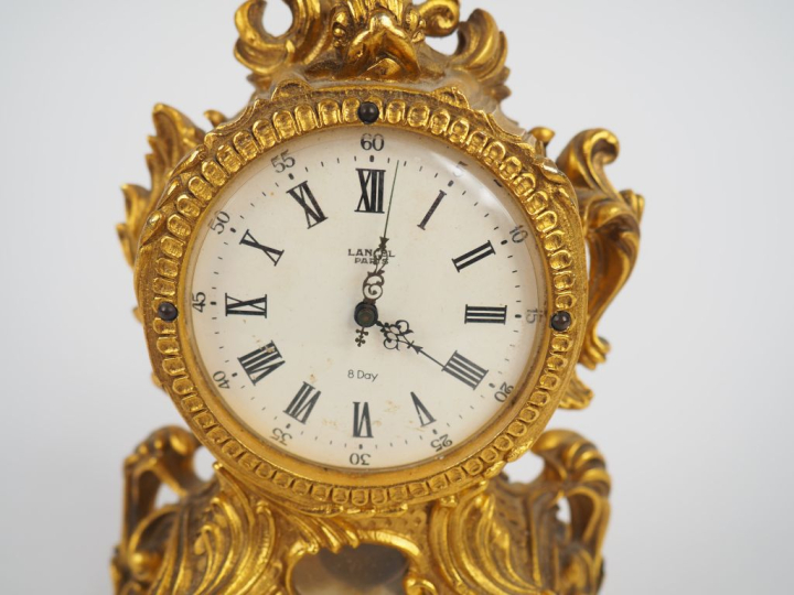 LANCEL, Paris Pendulette de style Louis XV en métal doré. Cadran rond 
