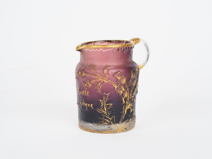 DAUM Nancy. Pichet en cristal mauve à décor émaillé doré de chardons, 
