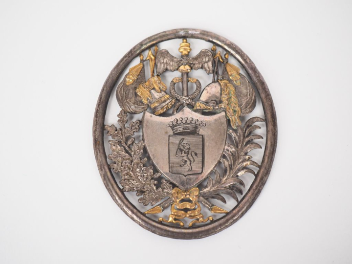 Plaque ovale en métal argenté et doré ou argent, à décor de trophée et