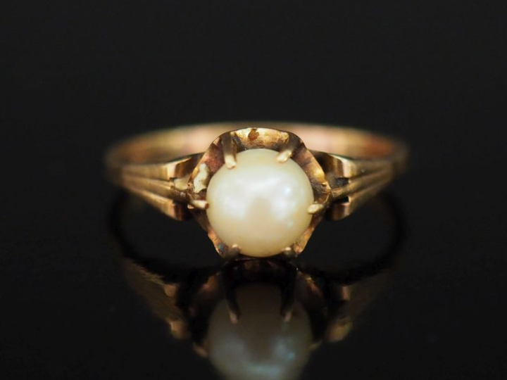Bague en or jaune 375, sertie en son centre d'une perle blanche. TDD. 