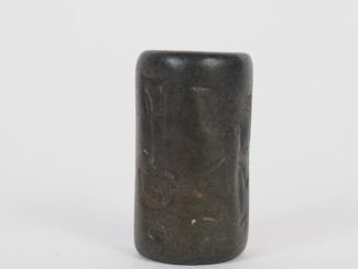 Vente aux enchères Orient ancien. Sceau cylindre en pierre noire décoré d’une scène de pr