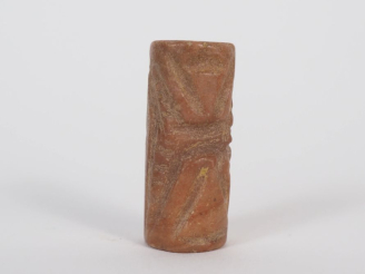 Vente aux enchères Orient ancien. Sceau cylindre en pierre rouge orné de traits formant d