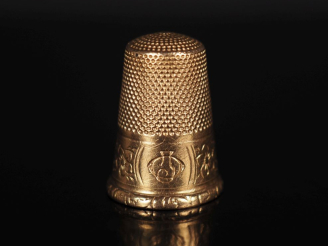 Vente aux enchères Dé à coudre en or jaune 750, à décor gravé de frise de fleurs.  H. 2,2