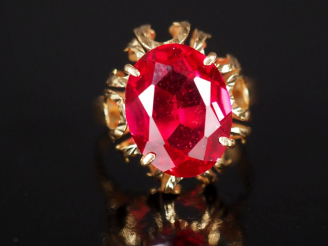 Vente aux enchères Bague en or jaune 750, sertie en son centre d'une pierre rouge.  Jolie