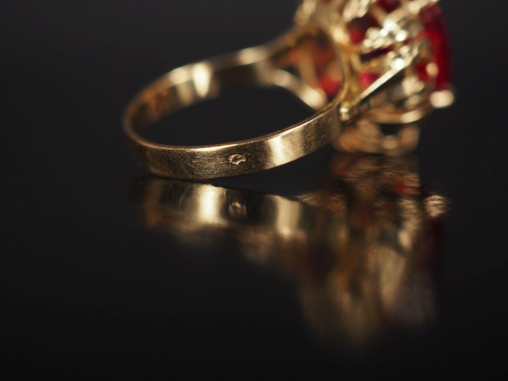 Bague en or jaune 750, sertie en son centre d'une pierre rouge.  Jolie