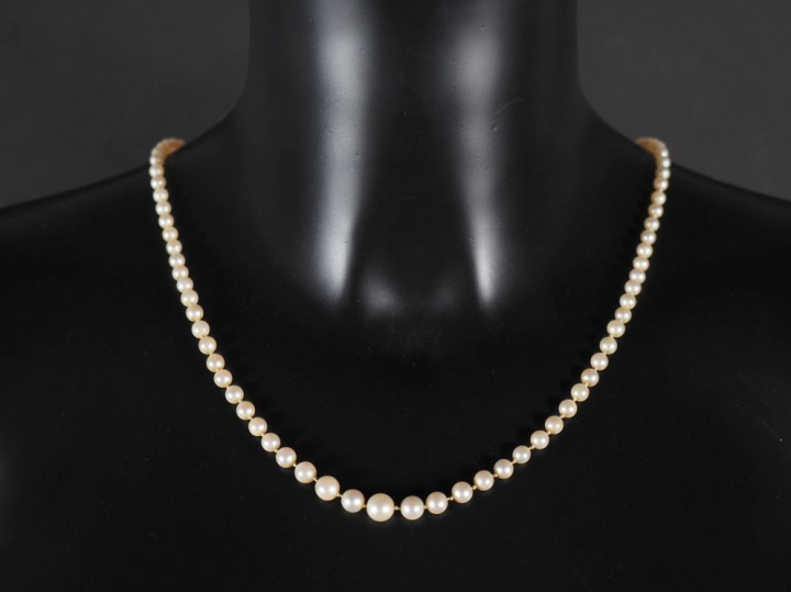 Collier de perles blanches disposées en chute.  Chainette de sécurité 