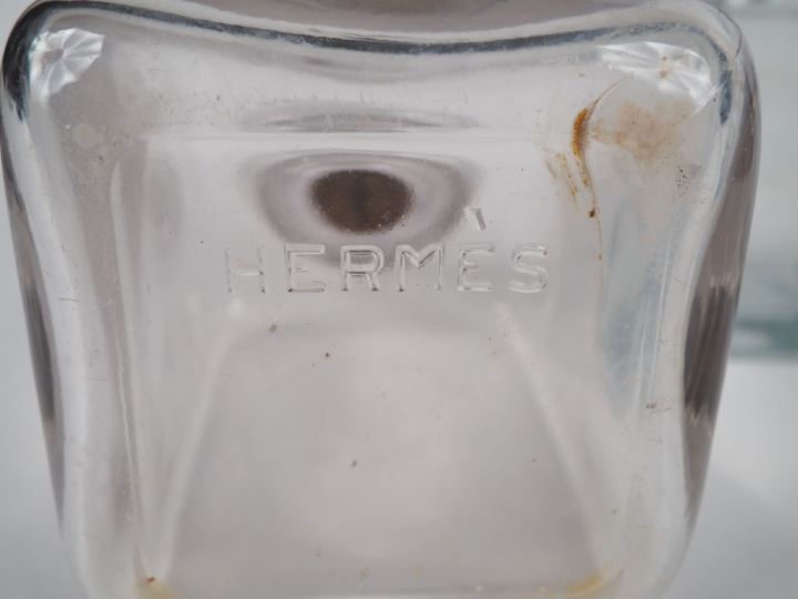 HERMES Garniture en verre comprenant quatre flacons et leur bouchon.  