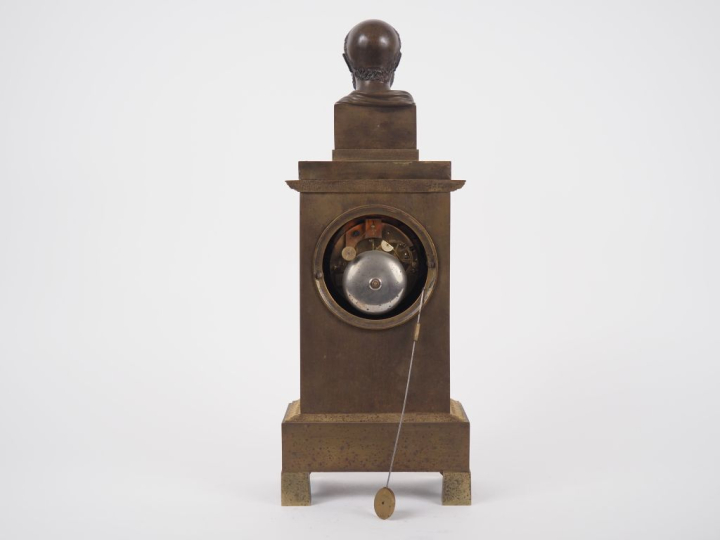 Pendule borne Restauration en bronze patiné et doré, surmontée d'un bu