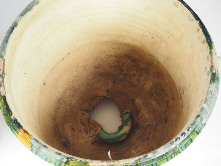 2 différents pots en terre vernissée verte nuancée de jaune, sur piédo