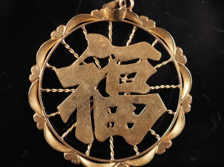 Pendentif ajouré en or jaune 750, à décor de caractère.  Diam. 4 cm Po