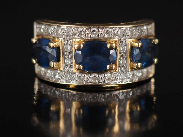 Bague bandeau en or jaune 750, sertie de trois saphirs entourés d'un p