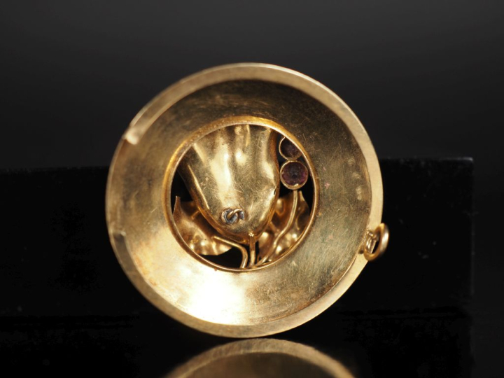 Broche ronde en or jaune 750, à décor ajouré d'une fleur et agrémentée