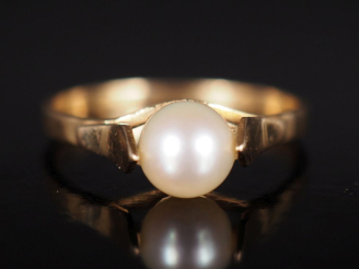 Vente aux enchères Bague en or jaune 750, sertie en son centre d'une perle blanche. TDD. 