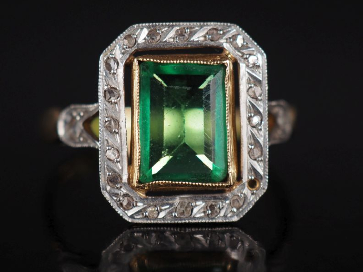 Bague en or jaune 750, sertie en son centre d'une pierre verte entouré