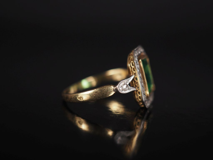 Bague en or jaune 750, sertie en son centre d'une pierre verte entouré
