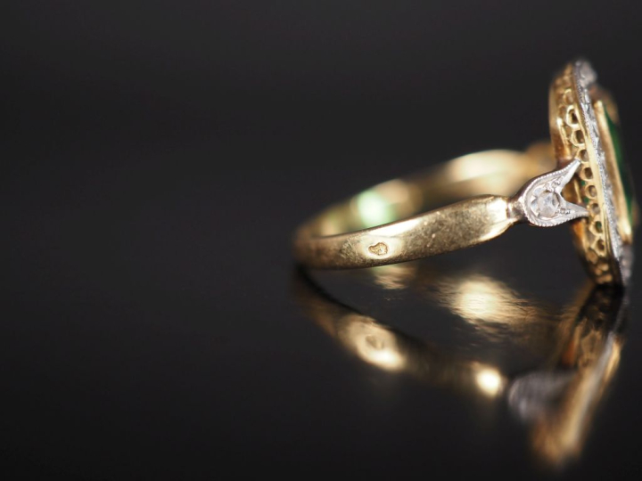 Bague en or jaune 750, sertie en son centre d'une pierre verte entouré